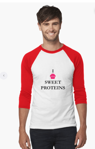 A young man smiling while wearing a white and red baseball-style shirt with the text 'I SWEET PROTEINS' and a cupcake graphic.
